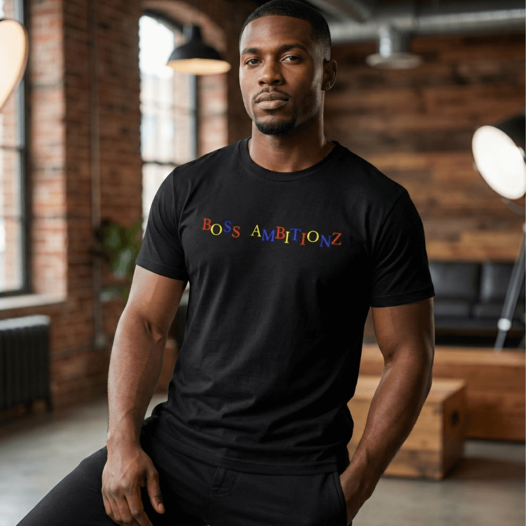 Man wearing a black Boss Leader Dreamer t shirt with colorful text in an indoor lounge