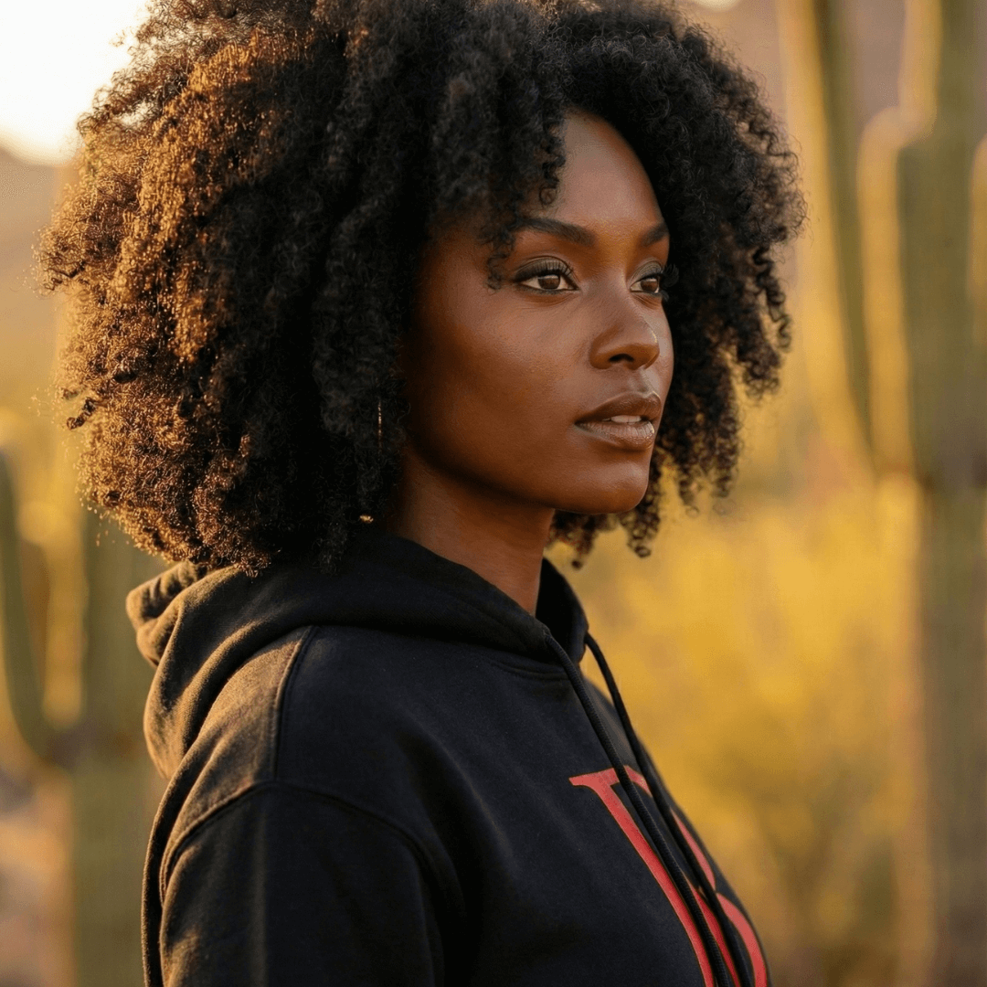 Woman wearing a black boss leader dreamer hoodie with red lettering in a desert setting