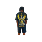 Back view of model showcasing Boss Ambitionz design: "Back view of model showcasing the Boss Ambitionz t-shirt with a striking gold winged emblem and 'Rise and Reign' slogan, paired with black shorts.