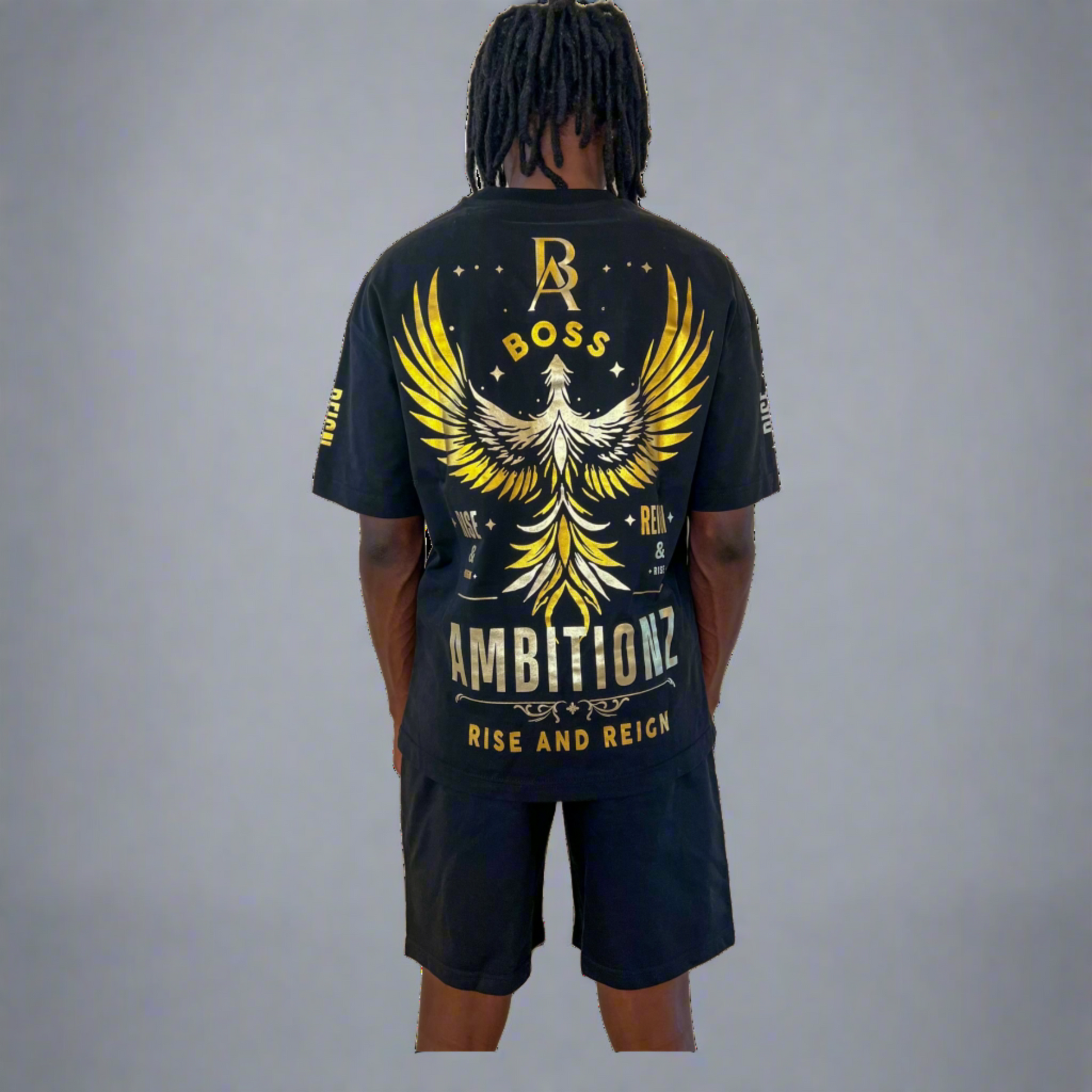 Back view of model showcasing Boss Ambitionz design: "Back view of model showcasing the Boss Ambitionz t-shirt with a striking gold winged emblem and 'Rise and Reign' slogan, paired with black shorts.