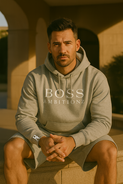 Man wearing a gray hoodie with 'BOSS AMBITIONZ' text, sitting outdoors.