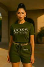 Woman wearing a green 'BOSS AMBITIONZ' t-shirt and shorts in an outdoor setting.