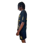 Side profile of DaKidswagg modeling Boss Ambitionz outfit: "Side profile of DaKidswagg modeling a black Boss Ambitionz t-shirt and shorts, showcasing the detailed gold text and logo designs