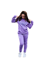 Rihanna posing in a powerful stance showcasing Boss Ambitionz Lavender Luxe Reflective Sweatsuit