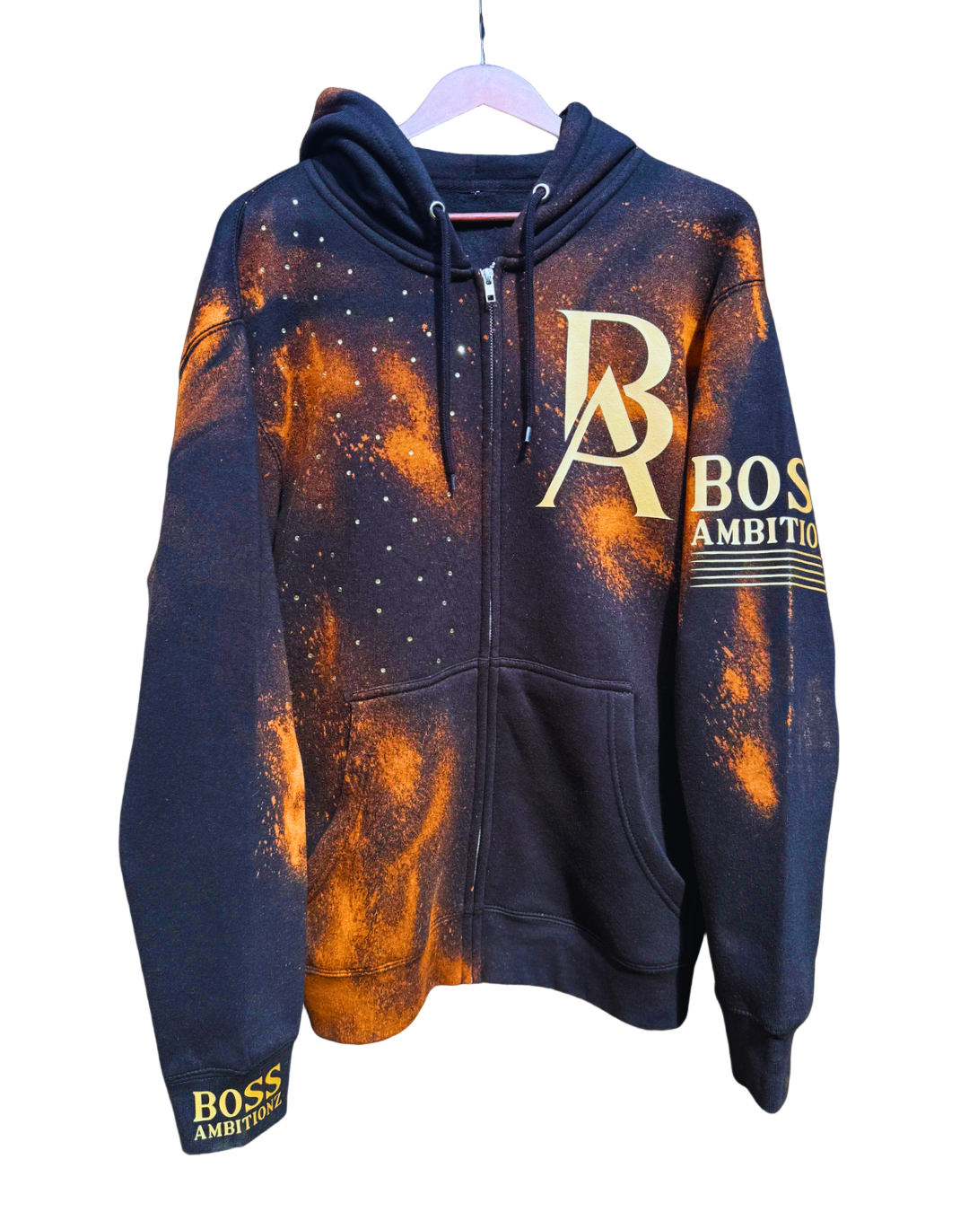 Front view of the Rustic Hustlers Rhinestone Zip-Up Hoodie by Boss Ambitionz, featuring an orange acid-wash finish on black fleece with gold BA logo, rhinestone detailing on the chest, and sleeve branding that reads “BOSS AMBITIONZ.