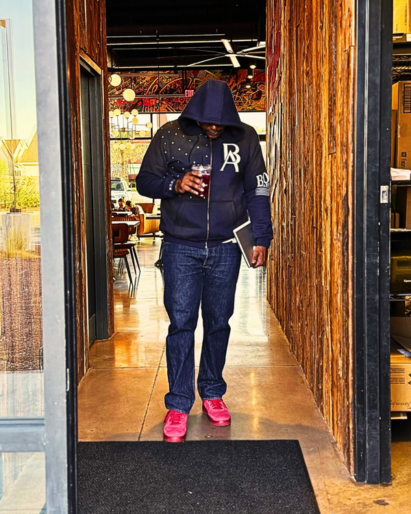 Model wearing Boss Ambitionz Rustic Hustlers Rhinestone Zip-Up Hoodie in navy with acid-wash finish and rhinestone detailing